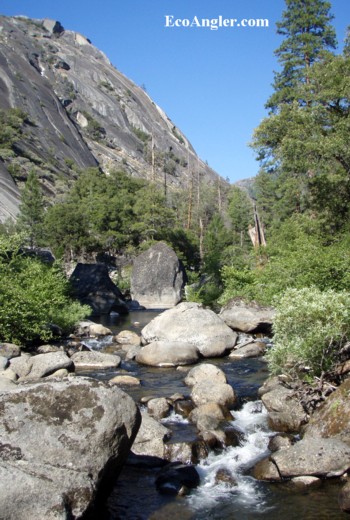 The North Fork of the Mokelumne River flows past a towering grantie domes and large boulders.