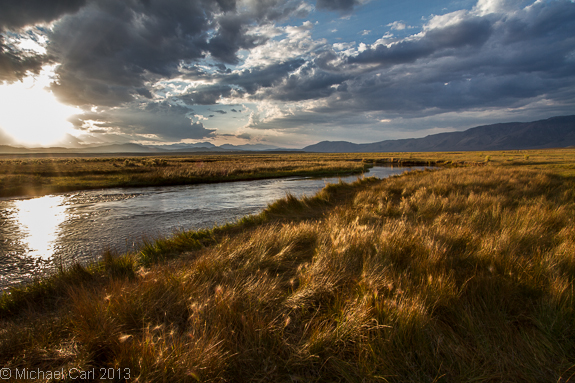 The Owens River flows through a flat high desert valley of grasses and sagebrush.